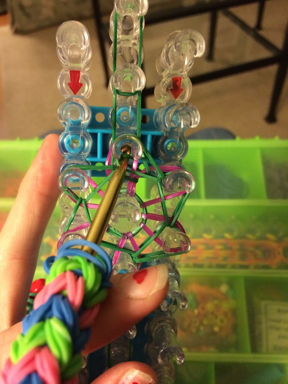Reach in the center peg and loop the first half of the ring base.