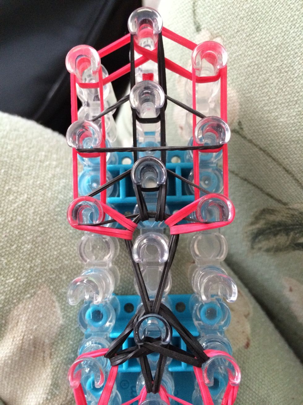 Reach in the middle peg and loop those three rubber bands