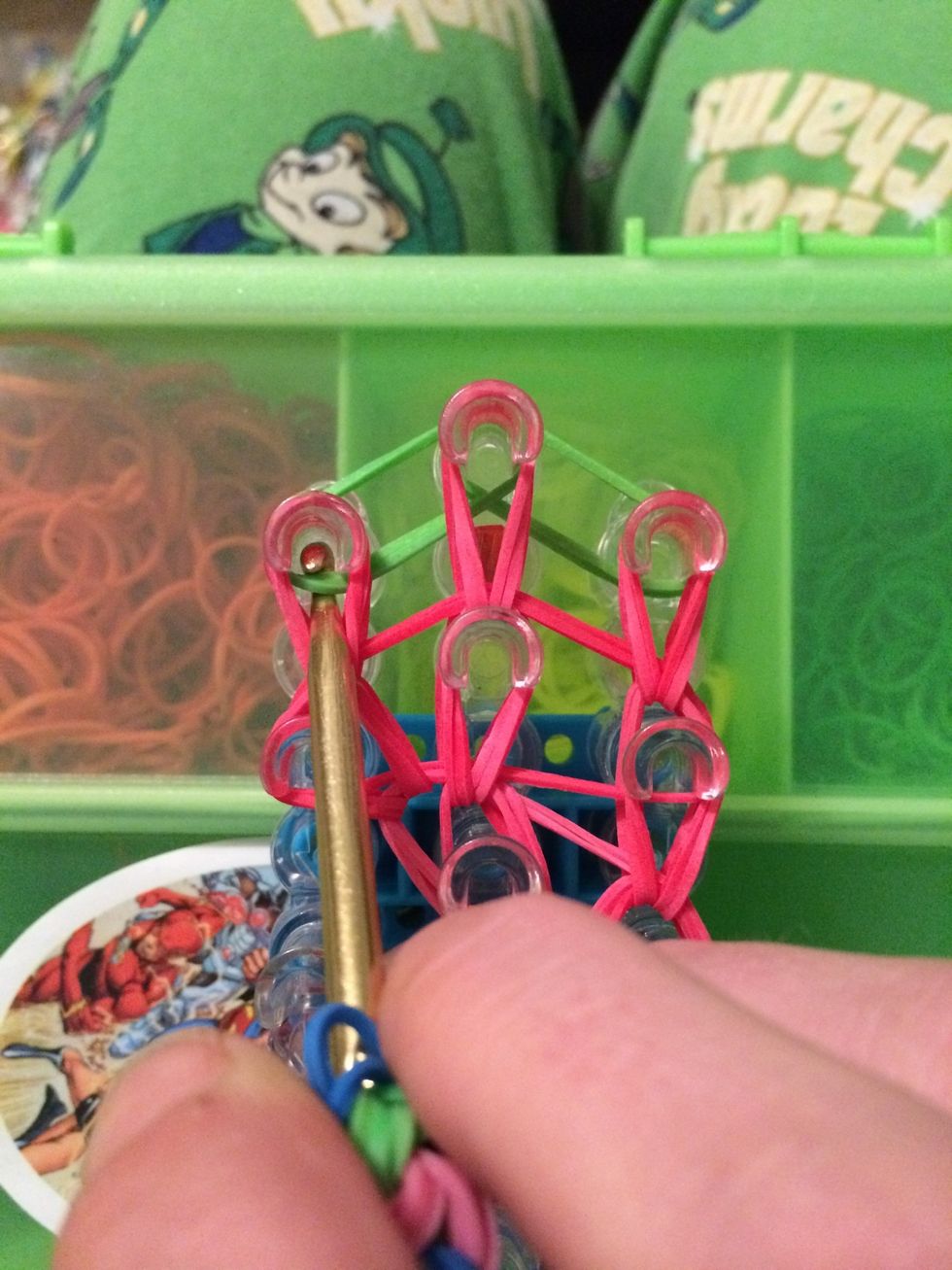 Reach in the peg and grab the 2 green bands. Move them to the center.