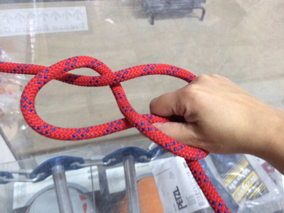 Reach through the hole to grab the short side (tag end) of the rope from behind.