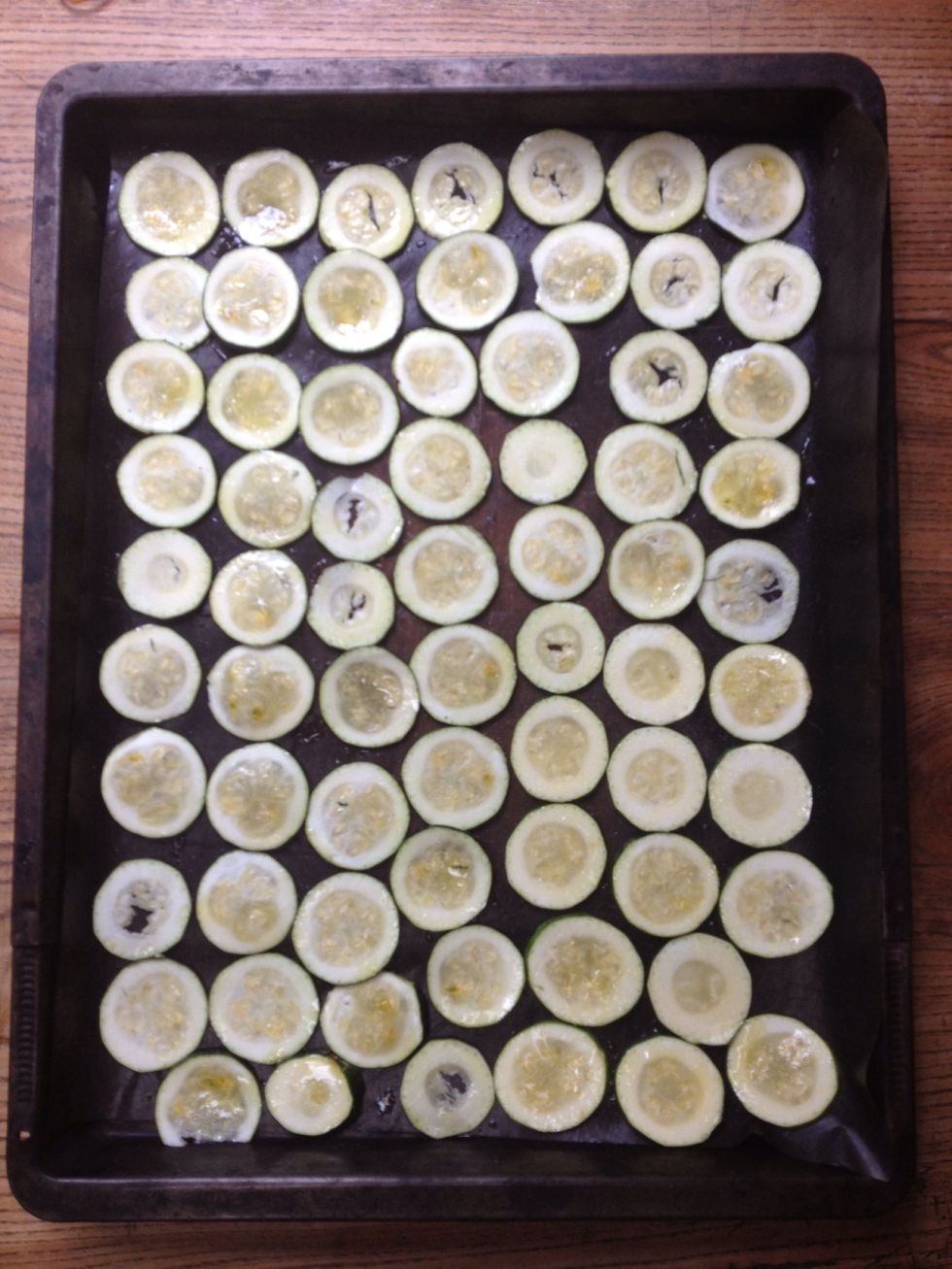 Recouvrez de papier sulfuris\u00e9 une plaque allant au four. D\u00e9posez-y les tranches de courgettes sans les superposer. Badigeonnez d'huile et saupoudrez l\u00e9g\u00e9rement de sel (mieux vaut resaler plus tard).