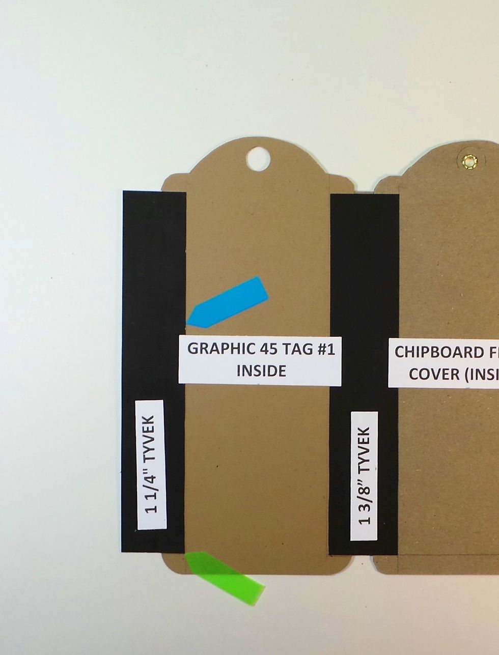Remove backing from one side of a 1 1/4" Tyvek strips. Add to the left side of Graphic 45 Tag #1. Line up vertical edge with 1/2" line on tag (blue arrow) & bottom with 3/8" line (green arrow)