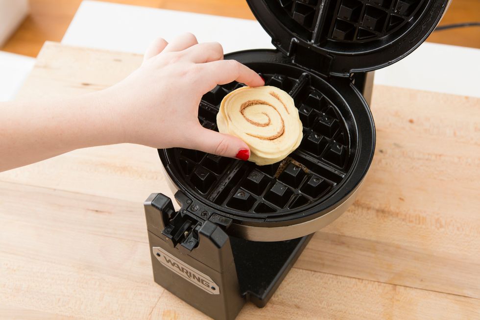 Remove cinnamon rolls from can and place one in the center of your waffle maker. 
