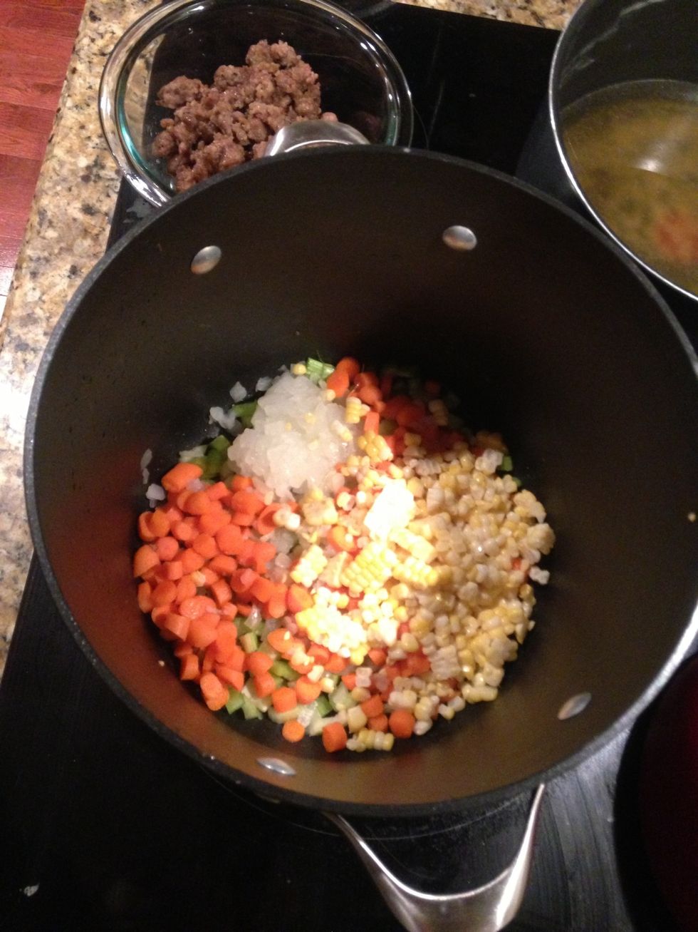 Remove sausage and drain off fat. Add onions, celery, carrots & corn. Saut\u00e9 3 min.