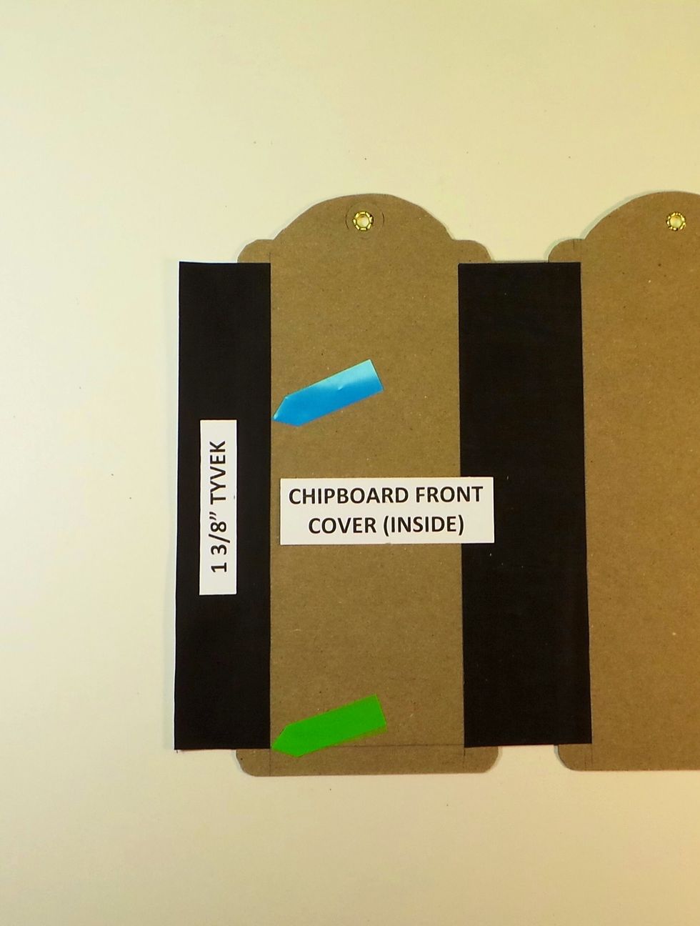 Remove tape backing from one side of 1 3/8" Tyvek strip. Add to the left side of the inside front cover. Line up vertical edge with 1/2" line on tag (blue arrow) & bottom with 3/8" line (green arrow)