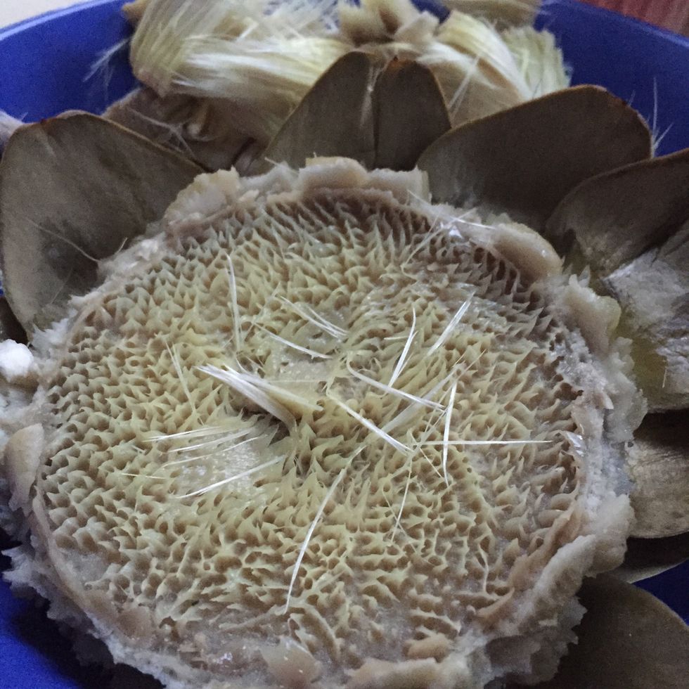 Remove the artichoke's choke (the hair-like filaments) from the artichoke's heart by pulling them.