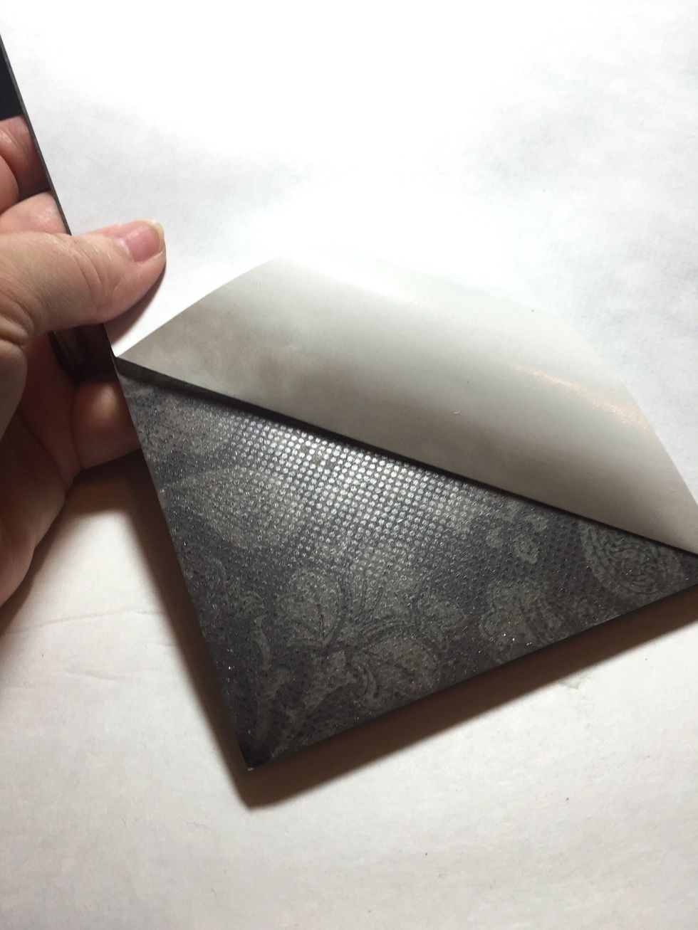 remove the backing to expose a corner of the now adhesive backed paper.