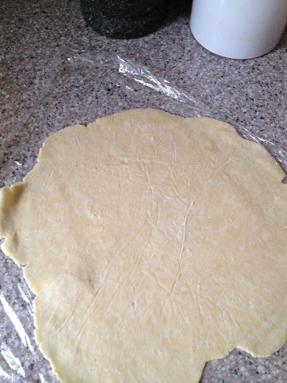 Remove the baking paper, save it for later in the process. Lift the dough onto the pie plate using the plastic wrap. Flip it so the wrap is on top.