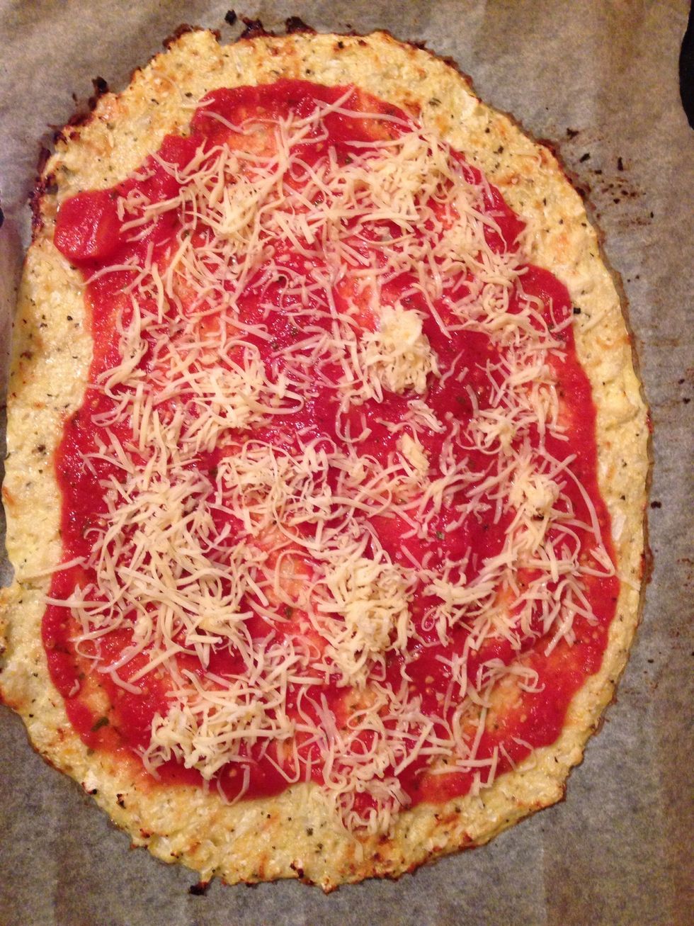 Remove the baking sheet from the oven. Now add tomato sauce and cheese.