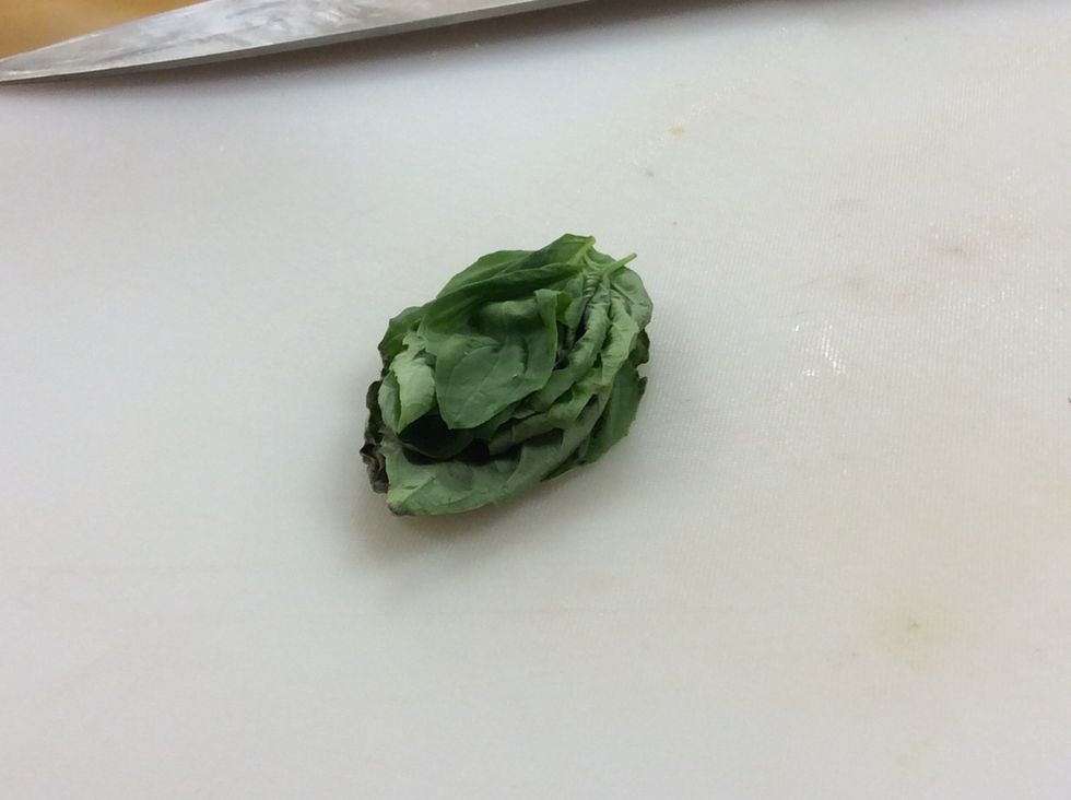 Remove the basil leaves from the stem, then stack them one of top of each other. This cutting technique is called chiffonade.