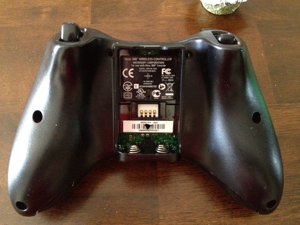 Remove the batter pack and take notice to the white barcode sticker. There is a screw right behind it. There are two on each handle of the controller and there is one on each side of the battery pack.