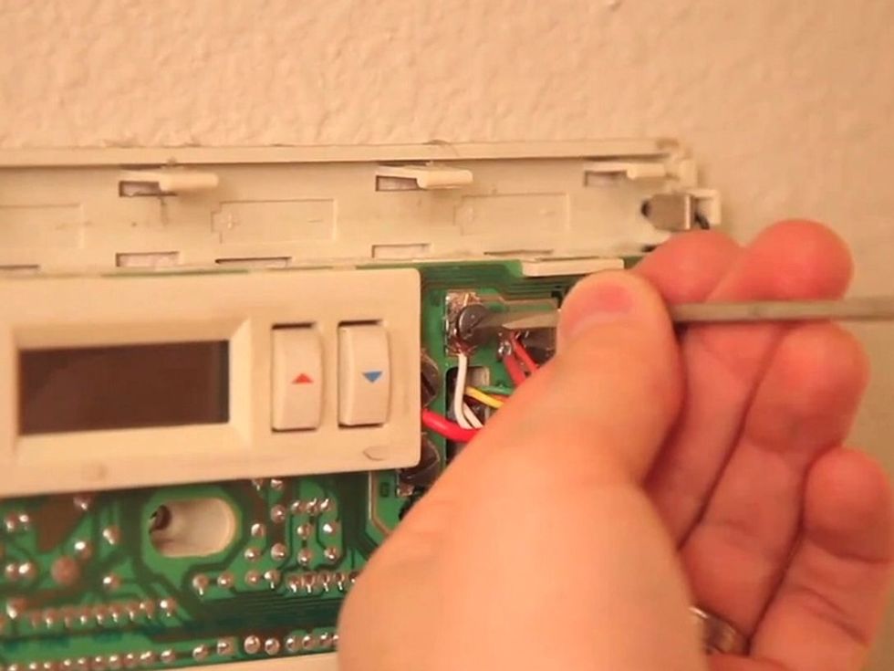 Remove the old thermostat. Take off the front plate, then disconnect the wires and mounting screws. Be careful not to let the old wires slip back into the wall.