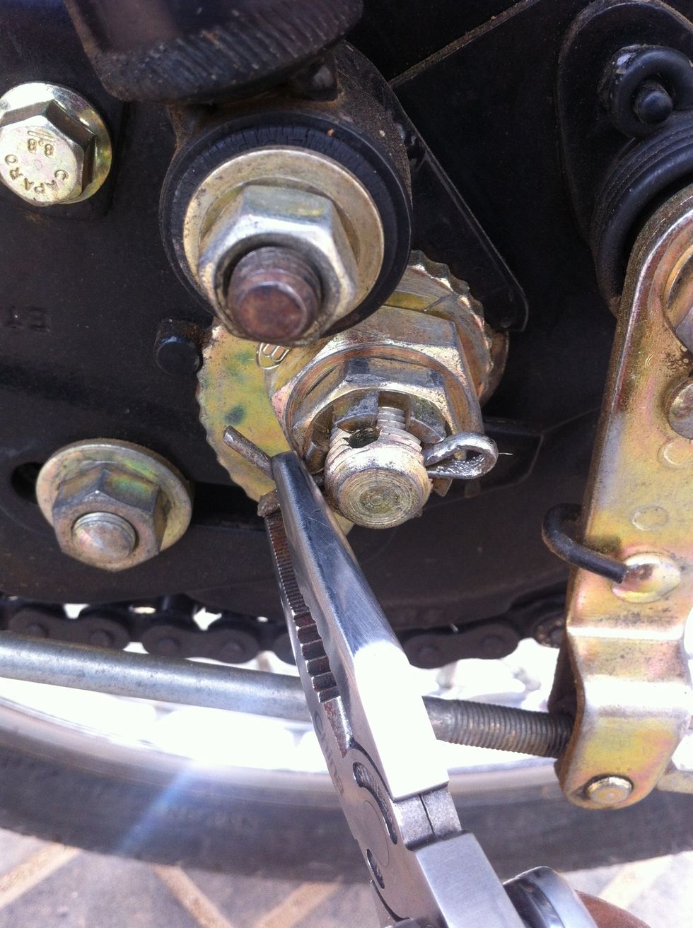 Remove the pin by straightening the bend ends. Some motorcycles may not have this pin.