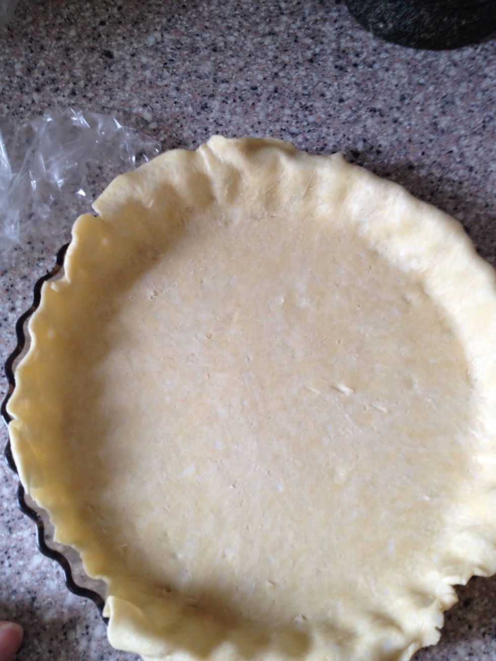 Remove the plastic and gently ease the dough into the pie plate by lifting the edge with one hand and pressing into the plate bottom with the other hand. Leave overhanging dough in place.