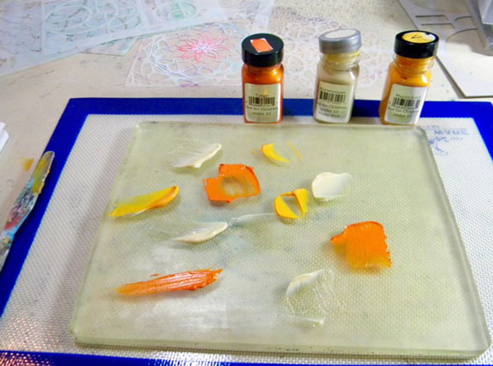 Remove the protective plastic from the Gelli Plate and place on a flat surface. Place dollops of paint onto the surface.  I used 3 colors. Less paint is better, especially when working in layers.