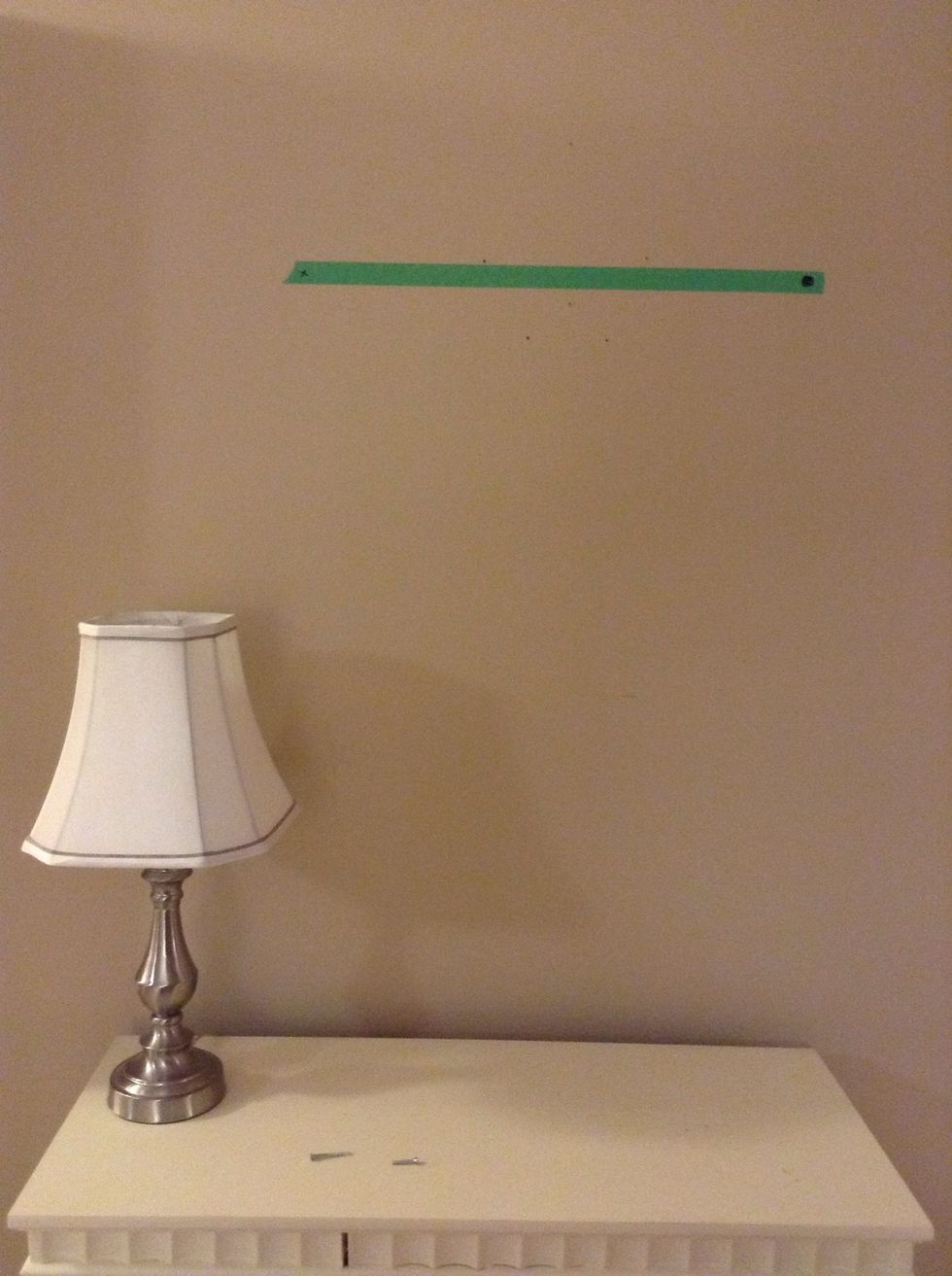 Remove the tape and place it on the wall. Measure both marks to make sure it's the right height from your furniture and again from the floor to make sure it's level. Adjust as necessary.
