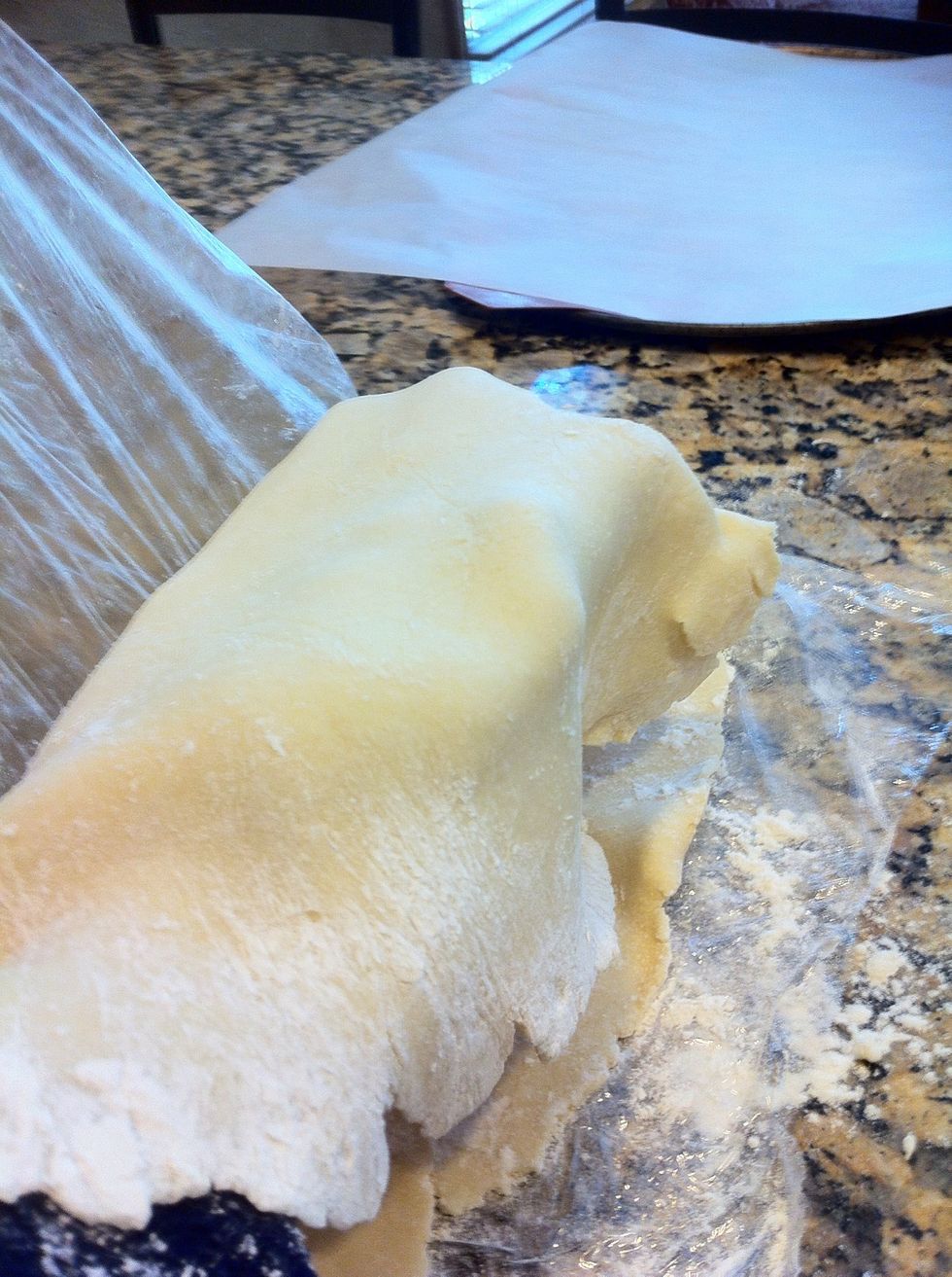 Remove top layer of wrap and take the bottom layer; flip up and over your arm to transfer dough to baking sheet