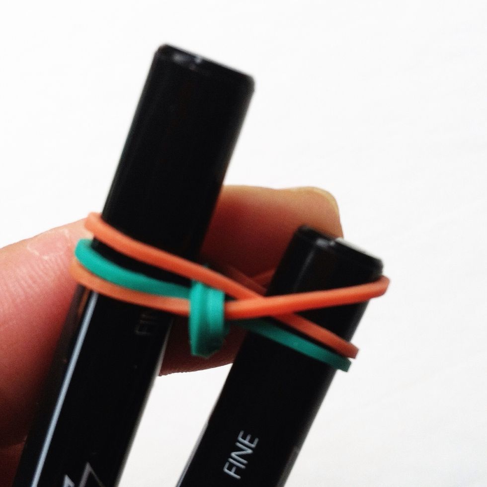 Repeat the process by pulling the bottom right elastic over the pen on the right.