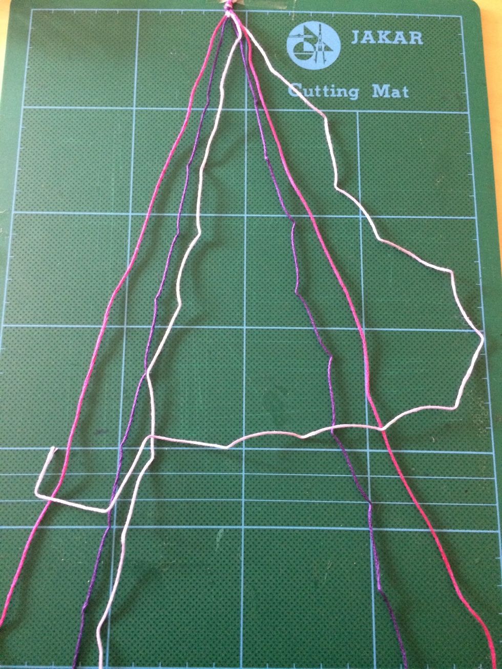 Repeat the same procedure from the right hand side. Starting with the pale lilac (far right) thread, make an inverted 'L' shape across the other threads and feed the end under the pink thread and pull