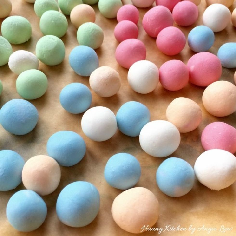 Repeat the same with the orange, blue, red and green dough. Place the rolled marble balls onto a plate lined with parchment paper. This can prevent the dough balls from sticking to the plate.