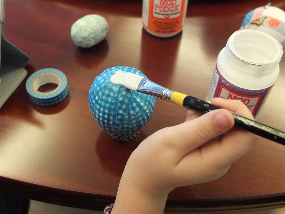 Resting the covered ball on the extra roll of tape paint the top half and leave it to dry.