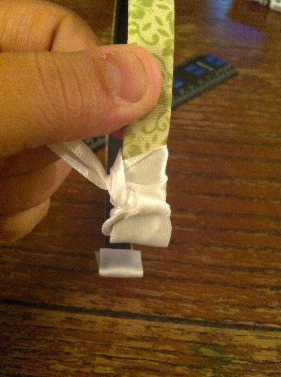 Ribbon through back an pull. When you pull, pull it to the opposite side of the loop first. To further tighten pull it back against itself. It should align itself in a natural diagonal.