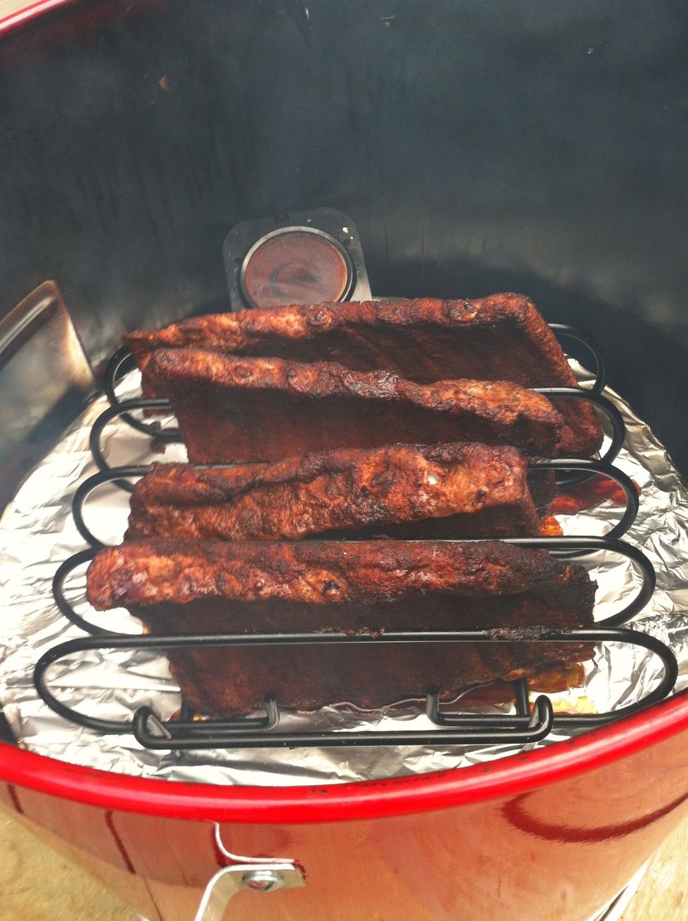Ribs after half an hour in the smoker. Don't forget to keep an eye on temp which should be between 325 & 350. Add wet woodchunks as necessary to keep the smoke going. Rub has turned into a crust.