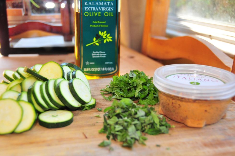 Rinse the zucchini then slice it in about 1/4" rounds like pictured. Chop the mint and oregano after rinsing. Place all ingredients in a bowl, add oil and seasoning.