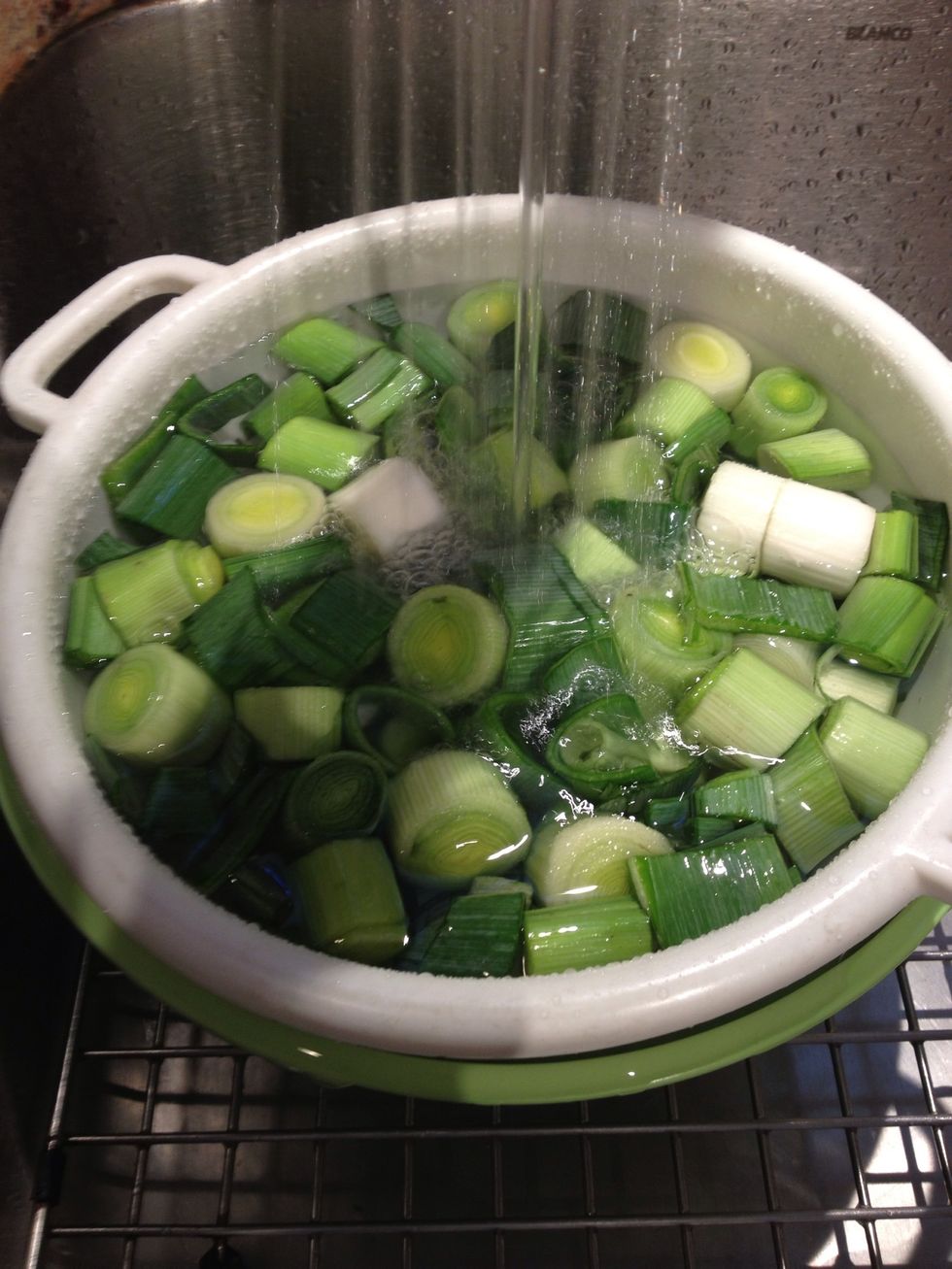 Rinse under cool running water, separating the pieces to dislodge as much grit as possible. Once the bowl is full, drain and refill. Soak the leeks for 5-10 minutes. Drain and rinse a final time.