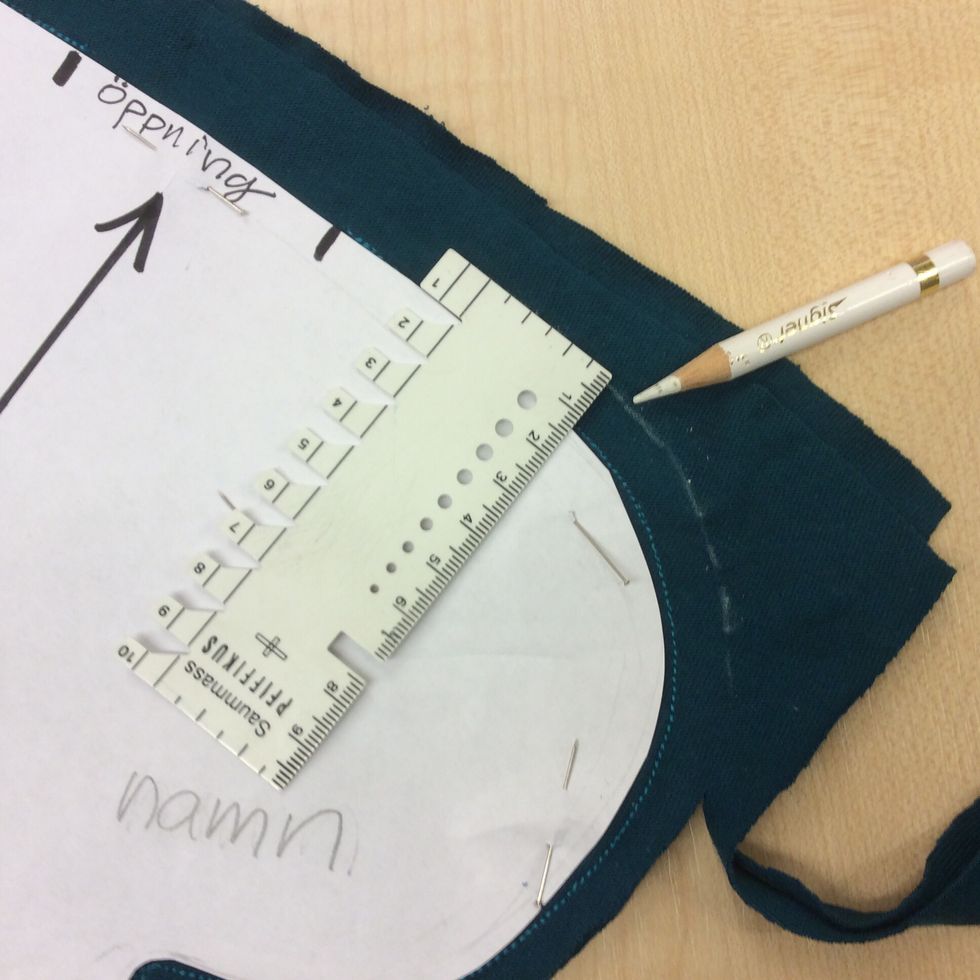 Rita en linje 1cm fr\u00e5n mallen med en tygpenna. Ta bort n\u00e5larna som sitter utanf\u00f6r mallen.