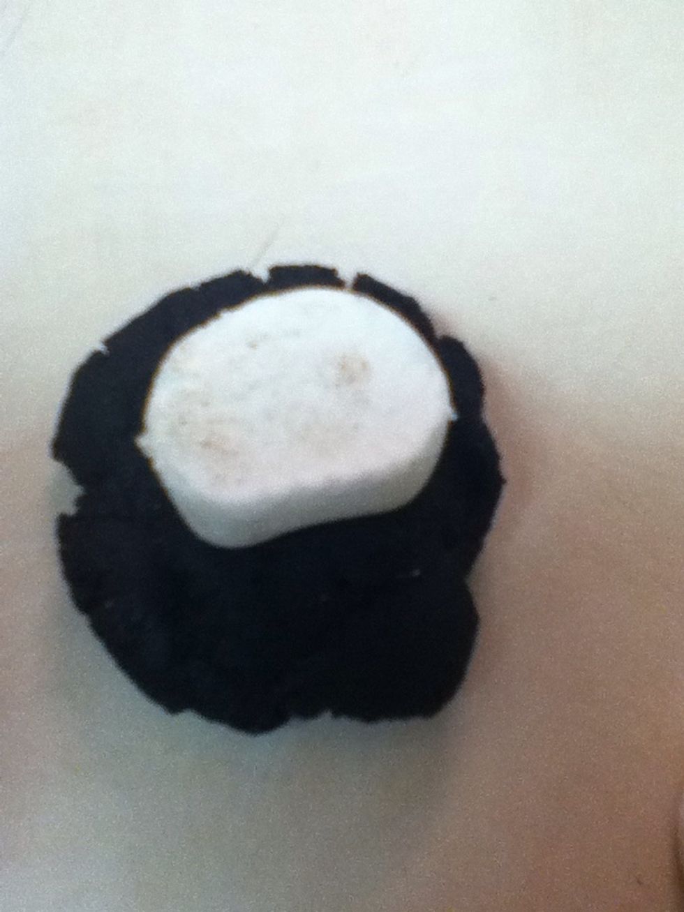 Roll about 1 tbsp of dough into a ball and flatten. Place half a marshmallow inside the dough.