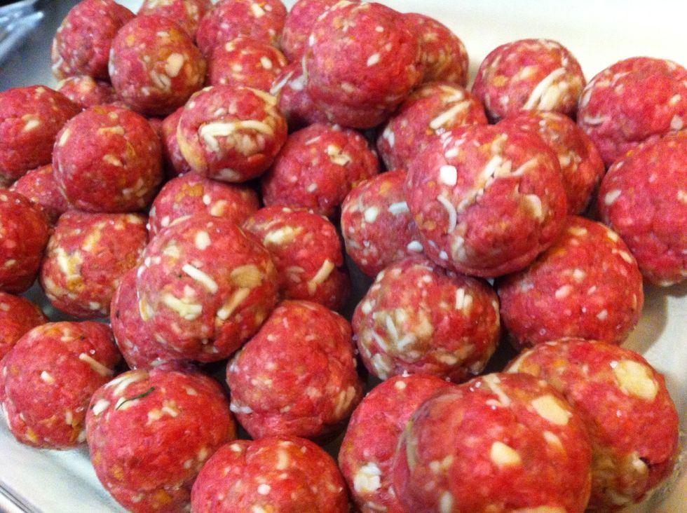 Roll it around between your palms until the outside is slick and uniform. Then toss it hard back and forth between cupped hands until you've got a tight, smooth meatball that won't break on the pan.