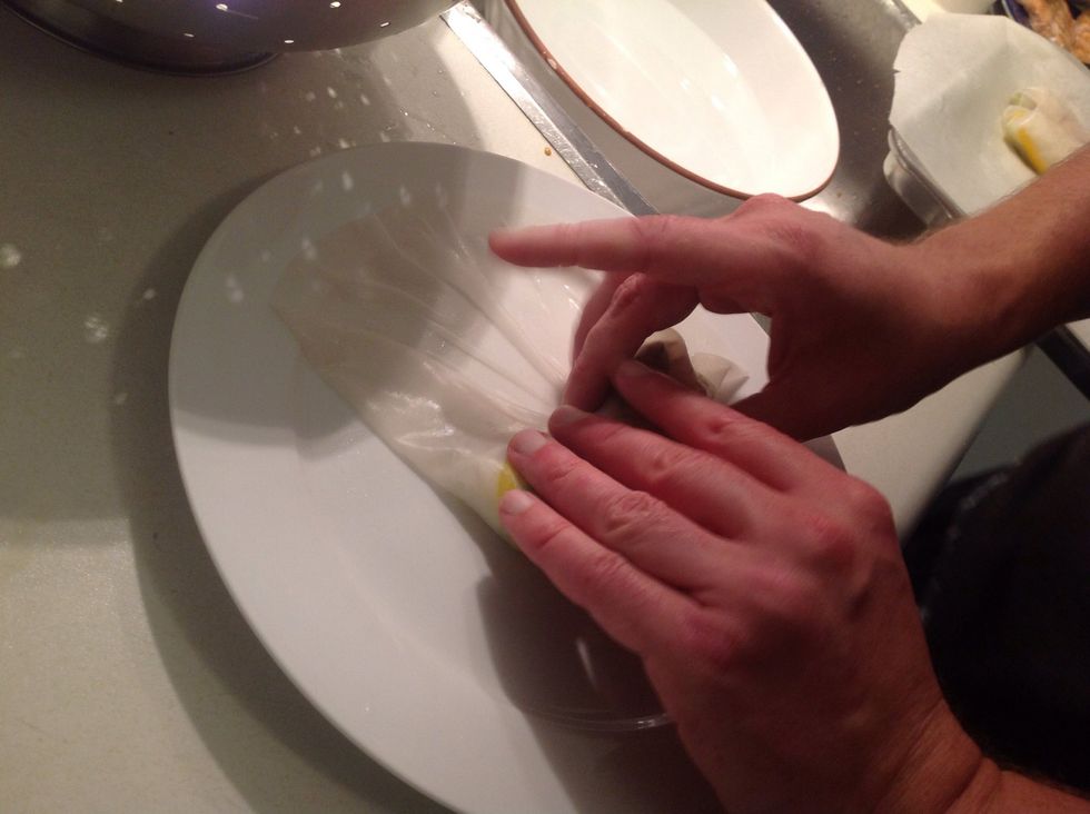 Roll it like a burrito by folding the paper closest to you over the filling. Then bring one side over toward the middle.