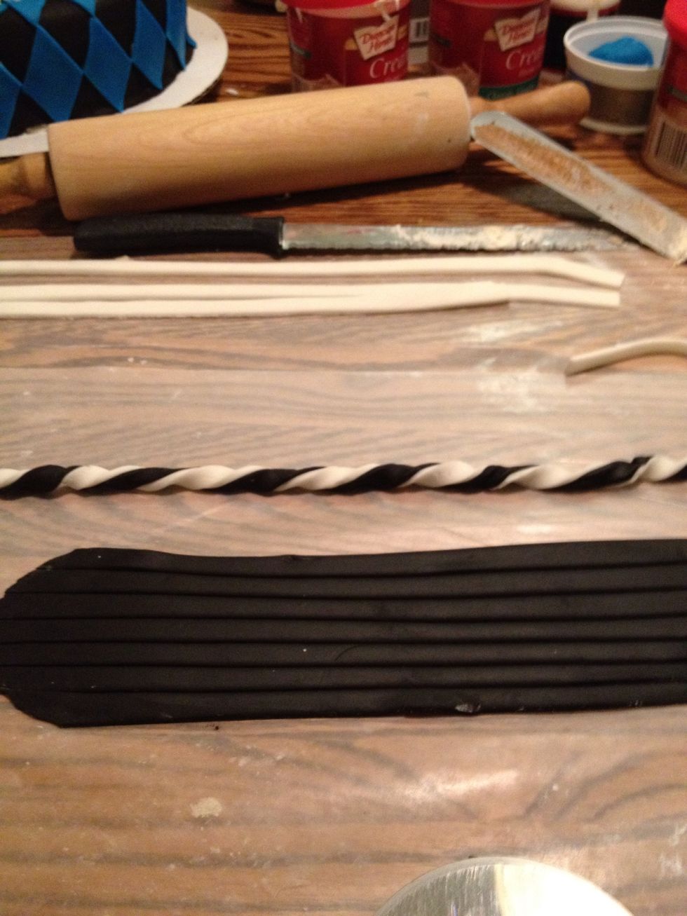 Roll out more black and white fondant. Cut into 1/2 in strips, place them in pairs, and twist them together.