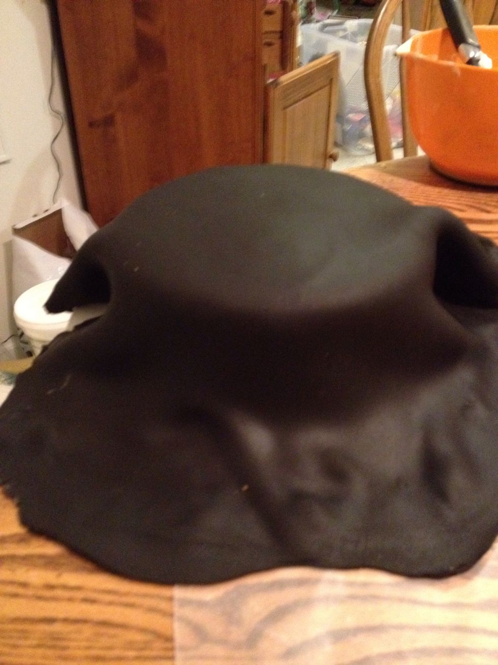 Roll out the black fondant using a rolling pin. Use powdered sugar if it sticks too much to the pin or surface. Place the rolled fondant on top of the 3 layers of cake.