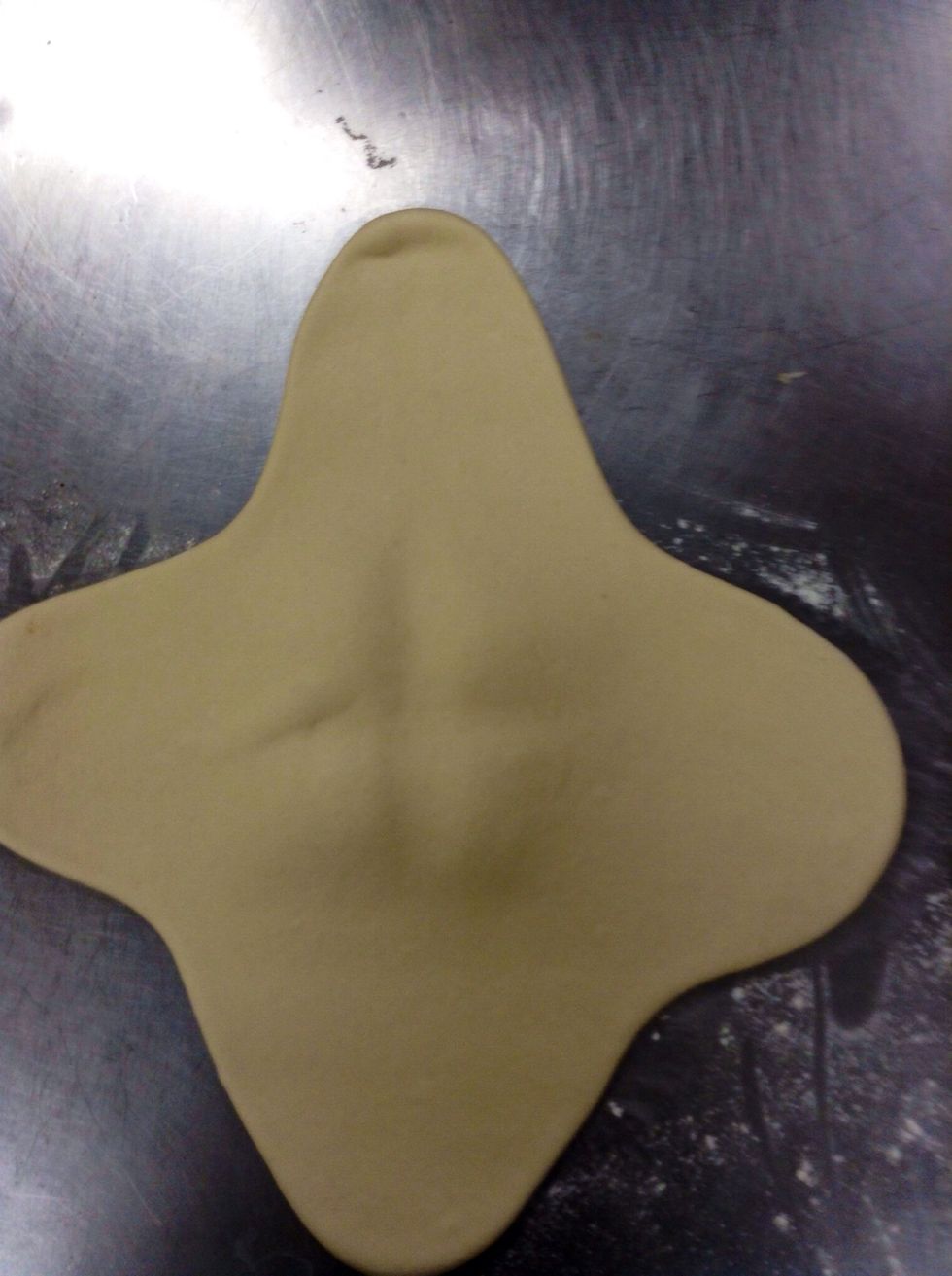 Roll out the corners of the square. Make sure to leave a lump of dough in the middle.