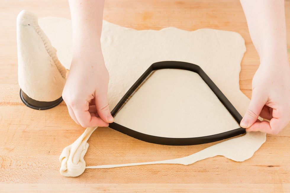Roll out your dough to 1/8 inch thickness. Cut out the cone shape using the dough cutter. Make sure to press firmly to have a clean cut. Then peel the dough back so your left with just the cone shape.
