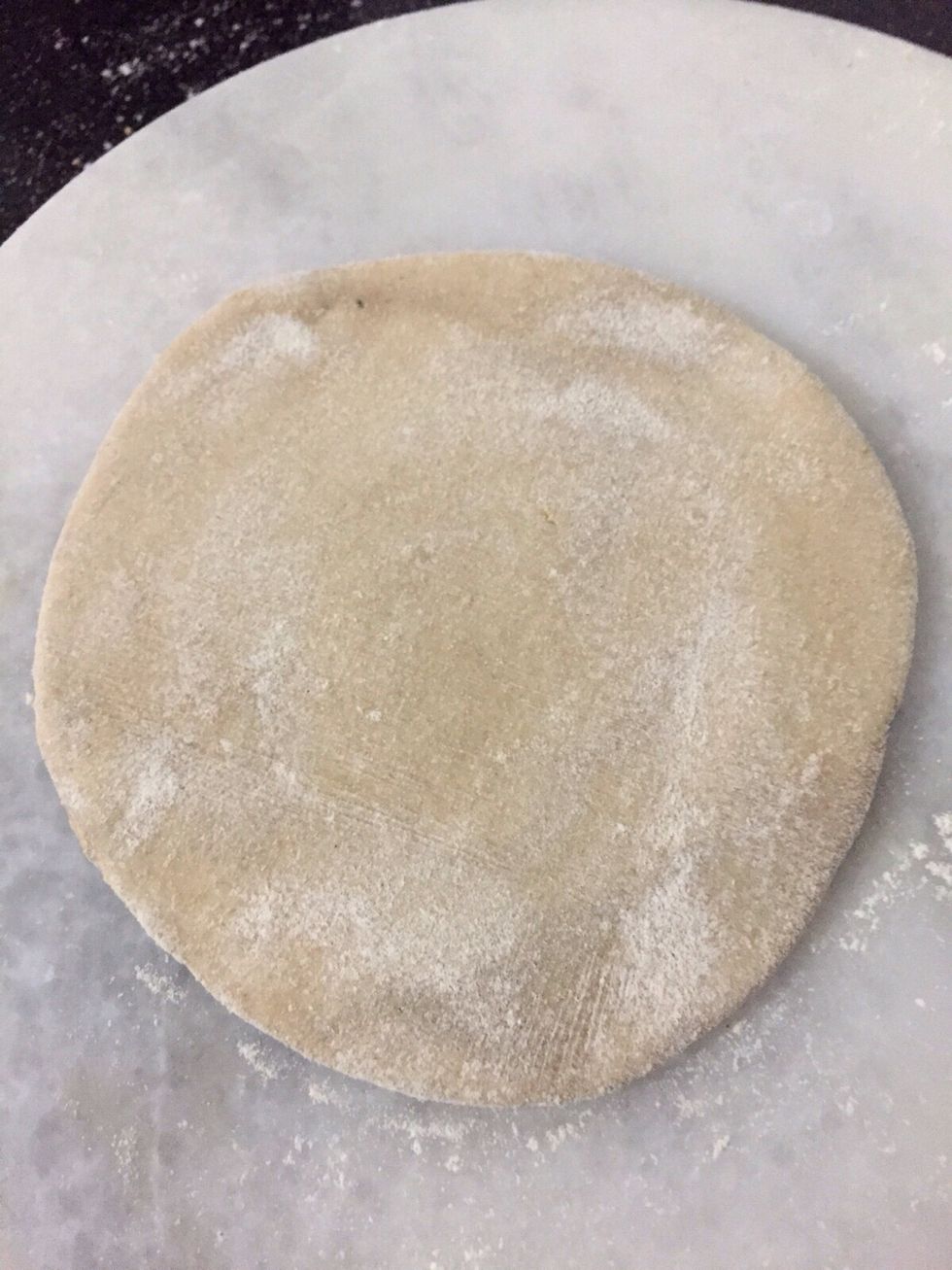 Roll the dough into small thick sheet . Put the stuffing in it .