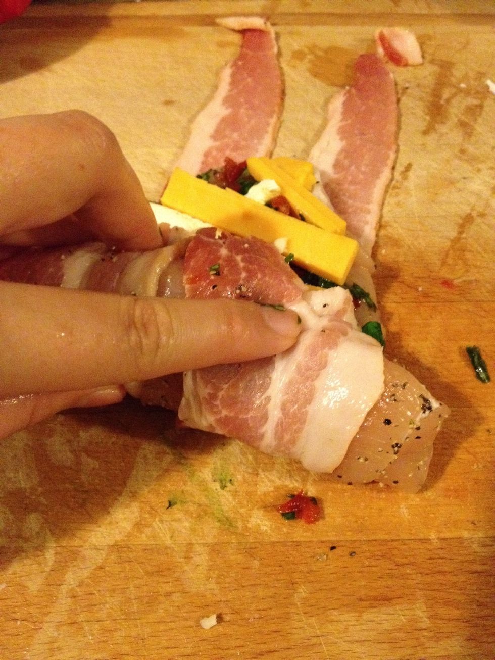 Roll up the chicken and wrap with strips of bacon.
