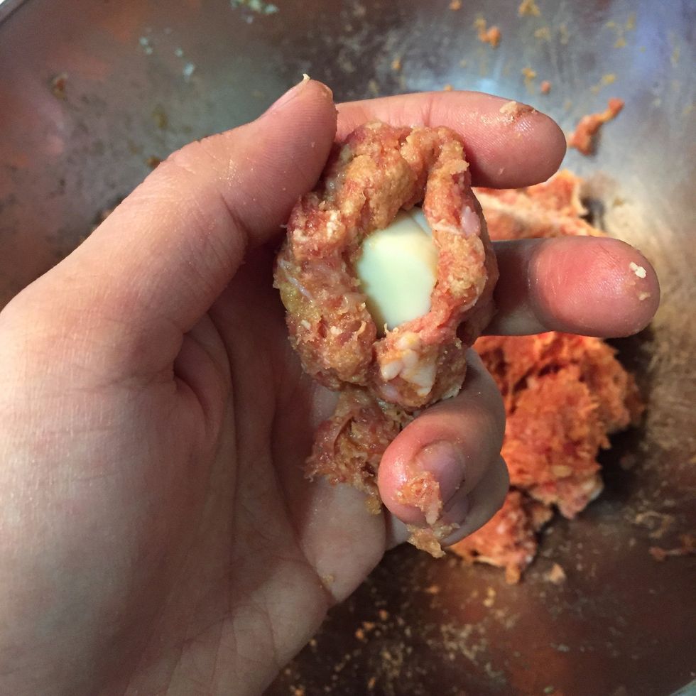 Roll your meatball and pinch the middle part. Then add piece off mozzarella cheese in it.