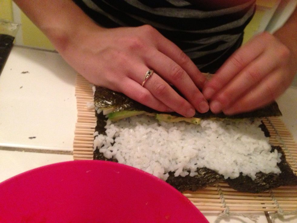 Rollllin, rollllin, Rollin up the sushi! Don't touch the bamboo yet, try to wrap the seaweed around all of your stuffing then keep rolling. The seaweed will stick to itself at the end of the roll.