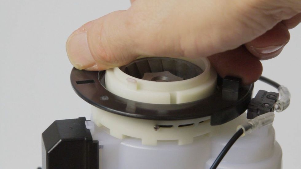 Rotate the black ring clockwise to fully expose the 3 adjustment windows in the white ring. There's a small screw in one of the windows. It's in the left window in this photo.