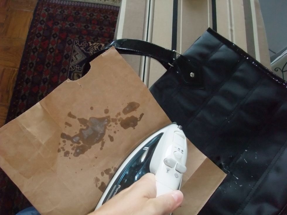Rotate the paper and apply the iron (over the paper) to different parts of the wax spill (2-3 seconds each time), until all the wax is all absorbed.