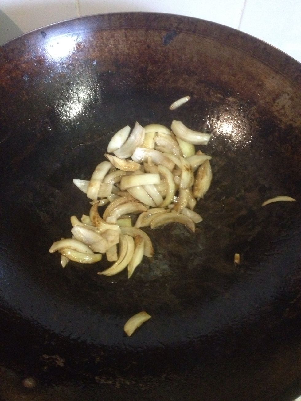 Roughly chop an onion and add to a hot wok stiring quickly.