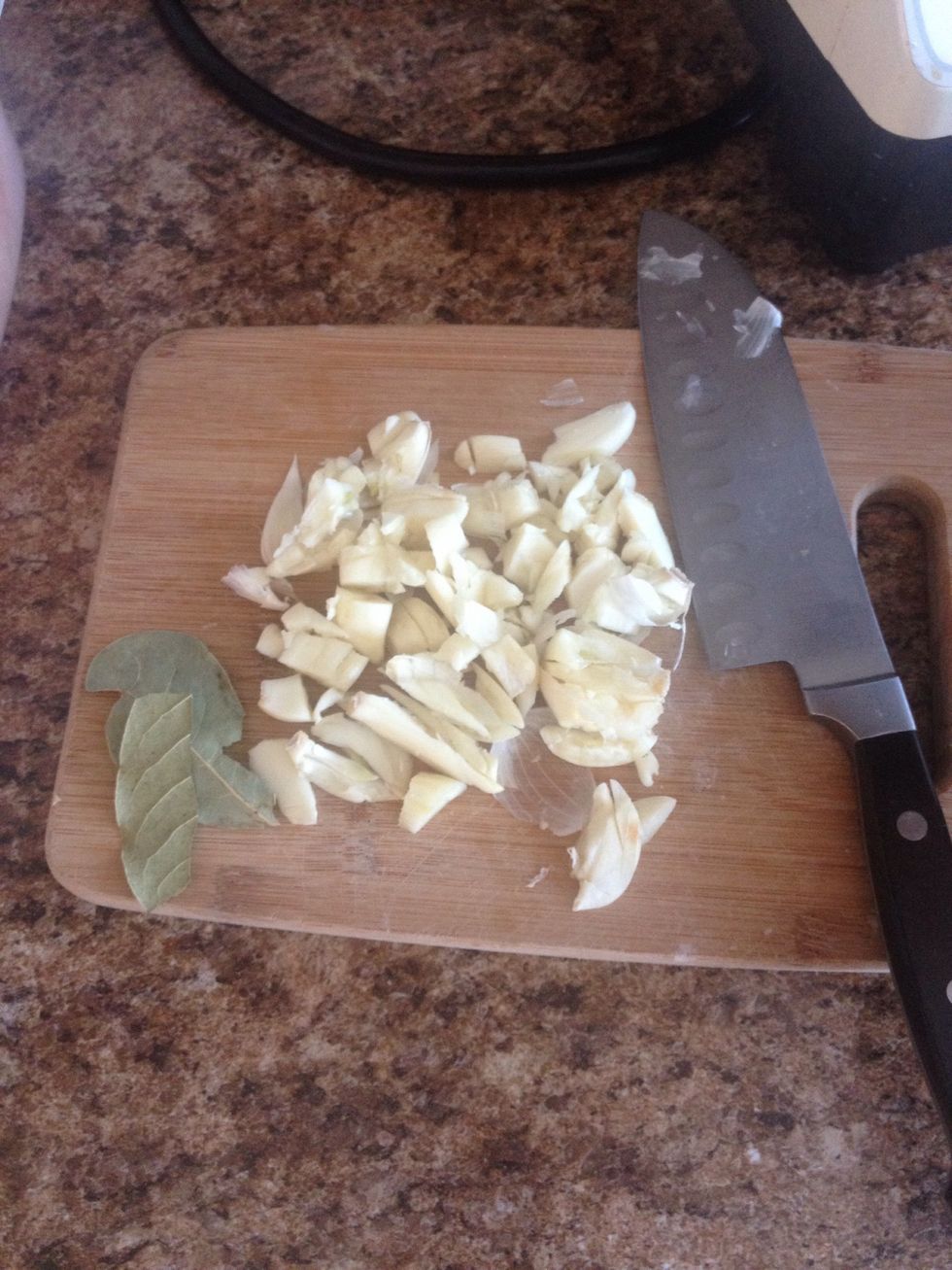 Roughly chop and crush a whole mess of garlic. Add two bay leaves.