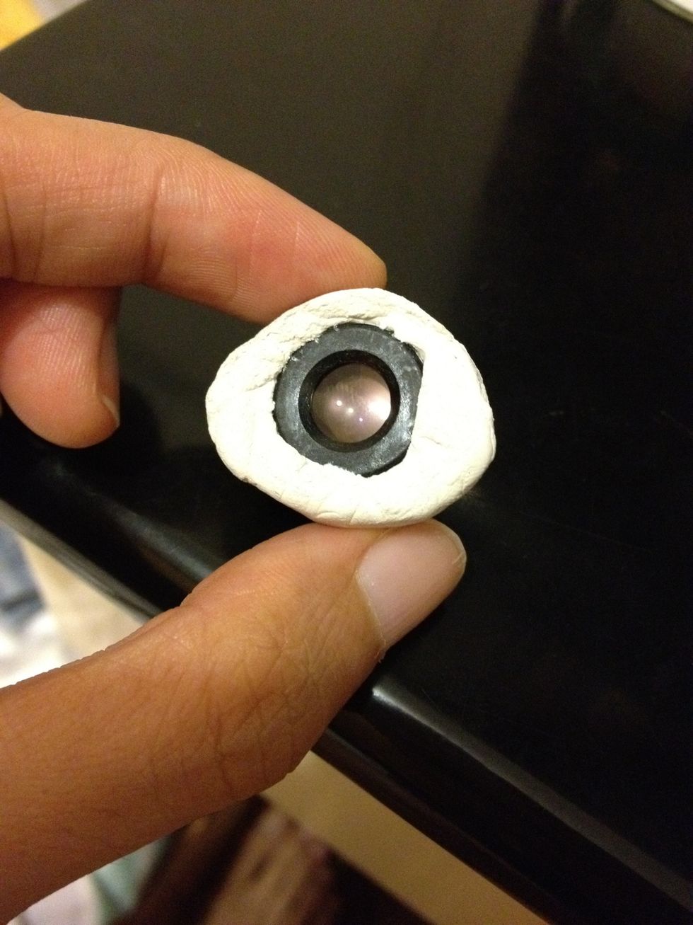 Round the lens with blu-tack (I've only got white ones at home)