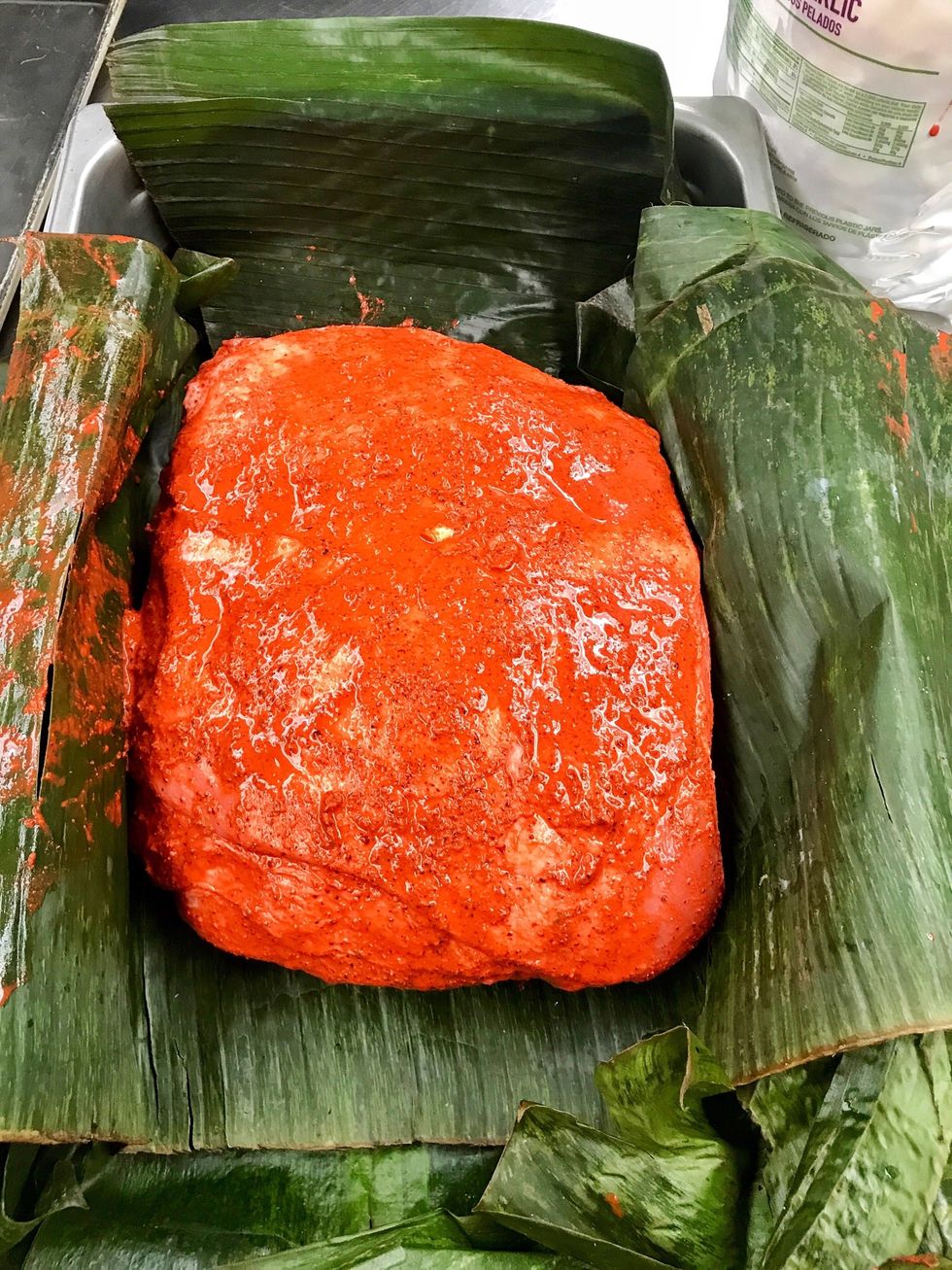 Rub marinade all over the pork butt and place into a hotel pan lined with the banana leaves.