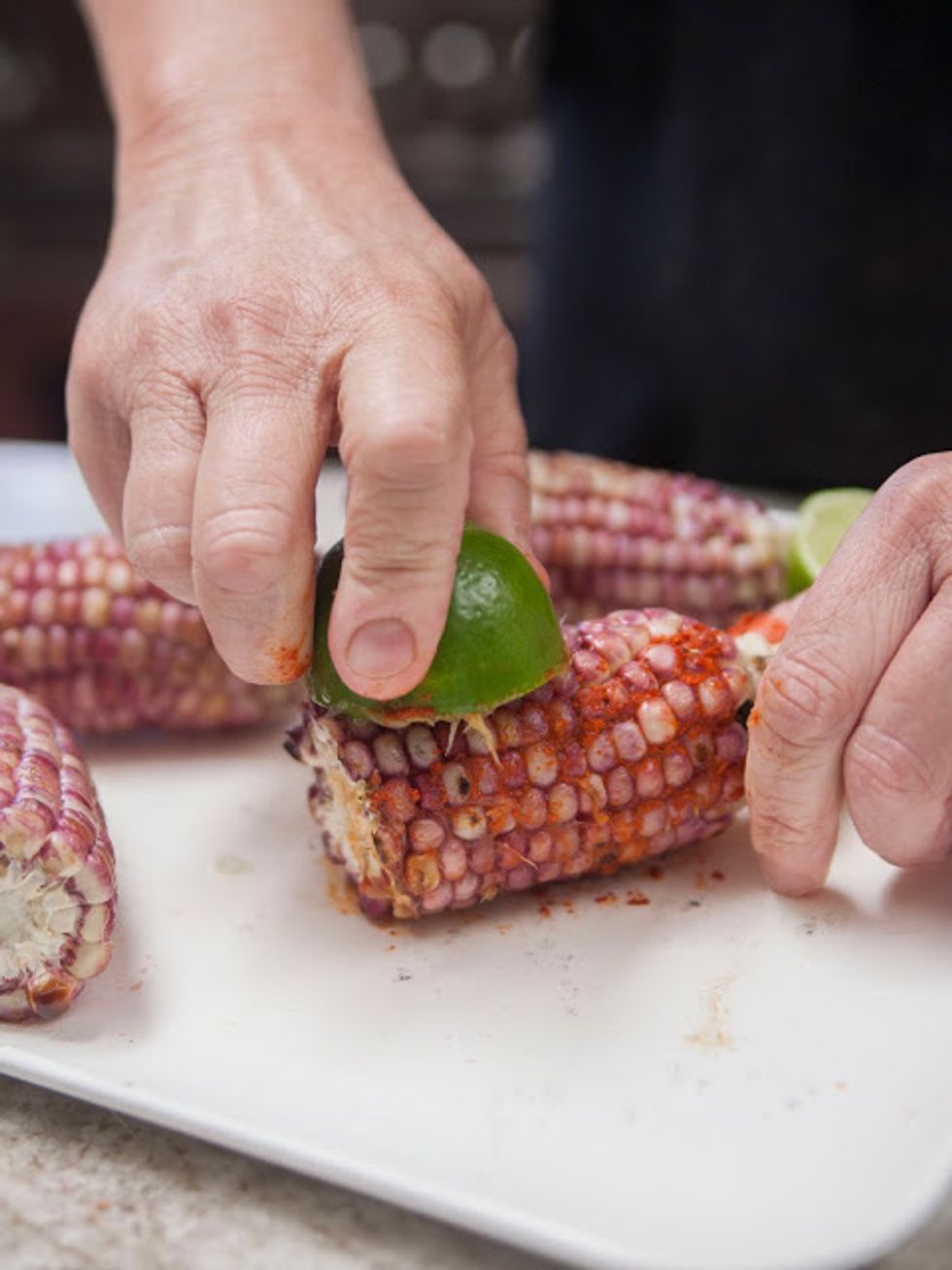Rub the chili-coated limes on the ears of corn while squeezing to get the juice out.