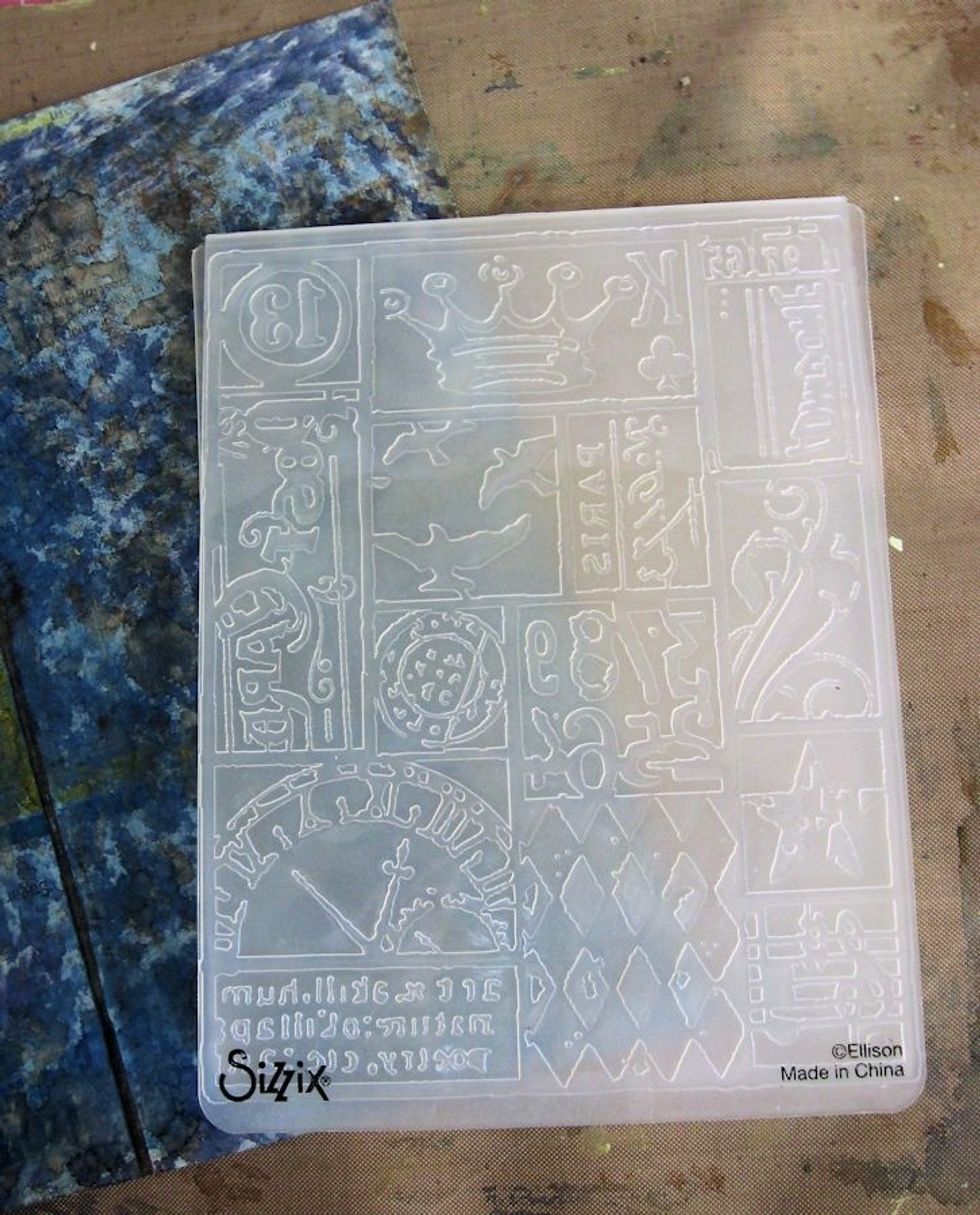 Run the inked surface through a die cutting machine using a texture fade.  I used Tim Holtz collage. Turn the box so that all surfaces are embossed. It's OK to overlap designs, or emboss upside down.