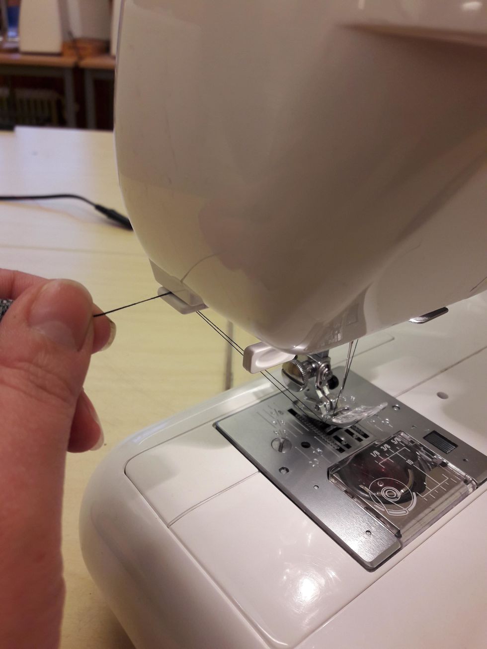 S\u00e4tt b\u00e5da tr\u00e5darna i springan p\u00e5 baksidan av maskinen och dra mot dig.